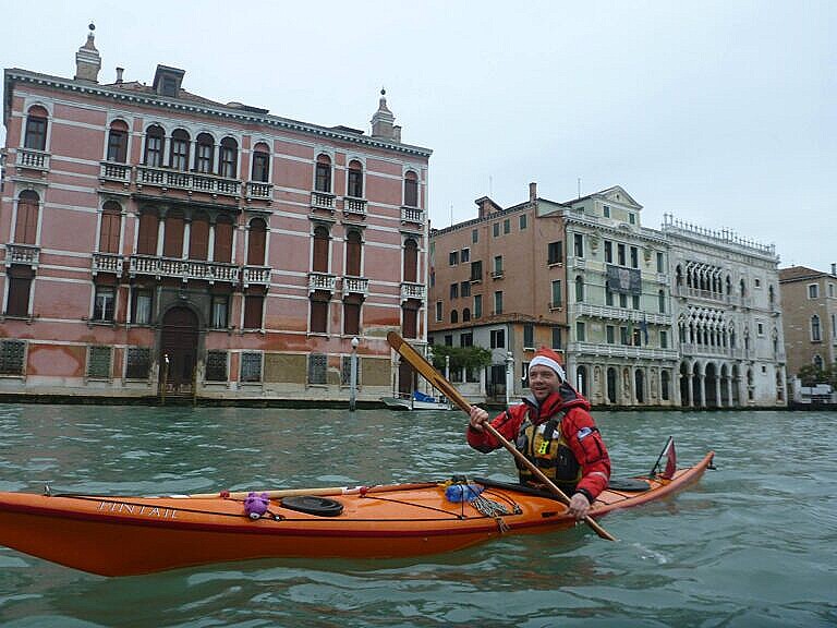René in a kayak on the Grand Canal, with a red jacket and a father Christmas hat